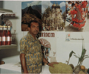 Harry Ganpat in zijn stand met Surinaamse producten op de Haagse Pasar Malam. Zijn hand rust op een nangka (jackfruit).