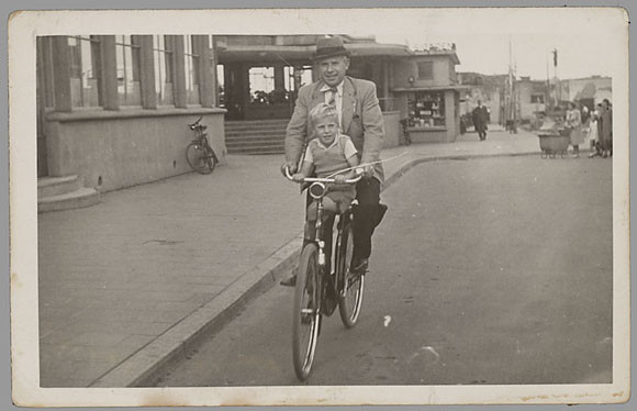 Cleomene Aridjis op zijn herenfiets met op het stuur zijn zoon Theo (Utrecht, 1941).