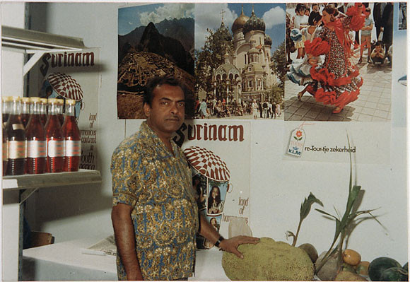 Harry Ganpat in zijn stand met Surinaamse producten op de Haagse Pasar Malam. Zijn hand rust op een nangka (jackfruit).